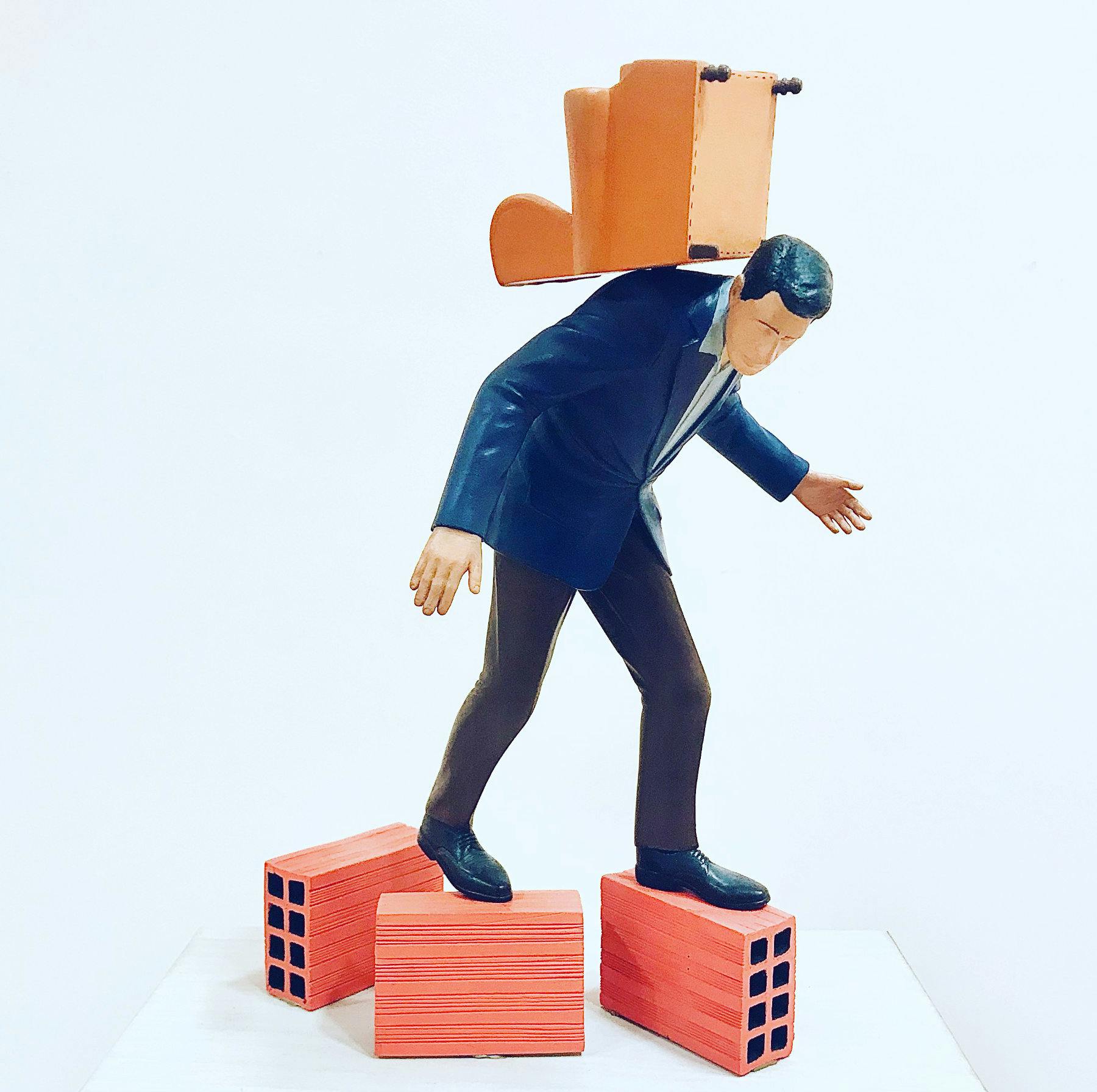 Figura de un hombre con traje haciendo equilibrismo sobre varios ladrillos